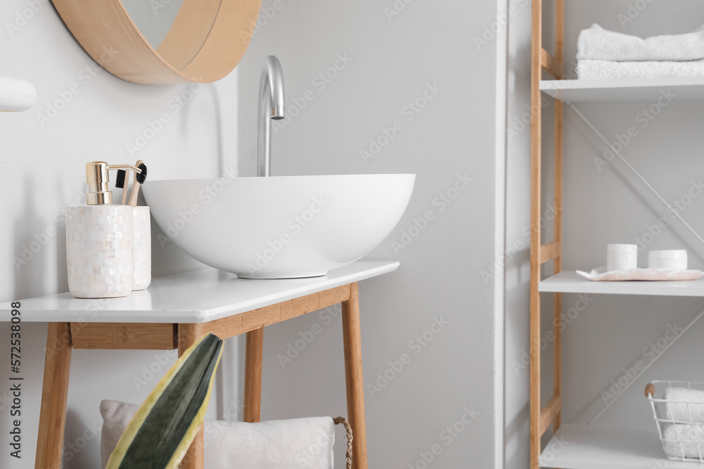 Table with modern sink, mirror and accessories in bathroom