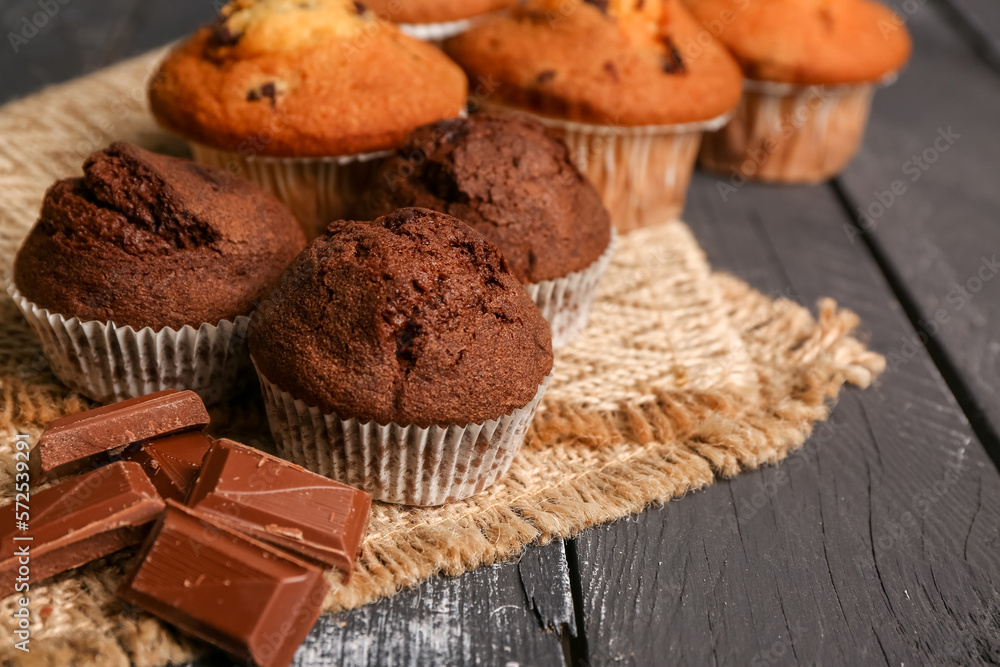 Sweet muffins and pieces of chocolate on dark wooden background, closeup