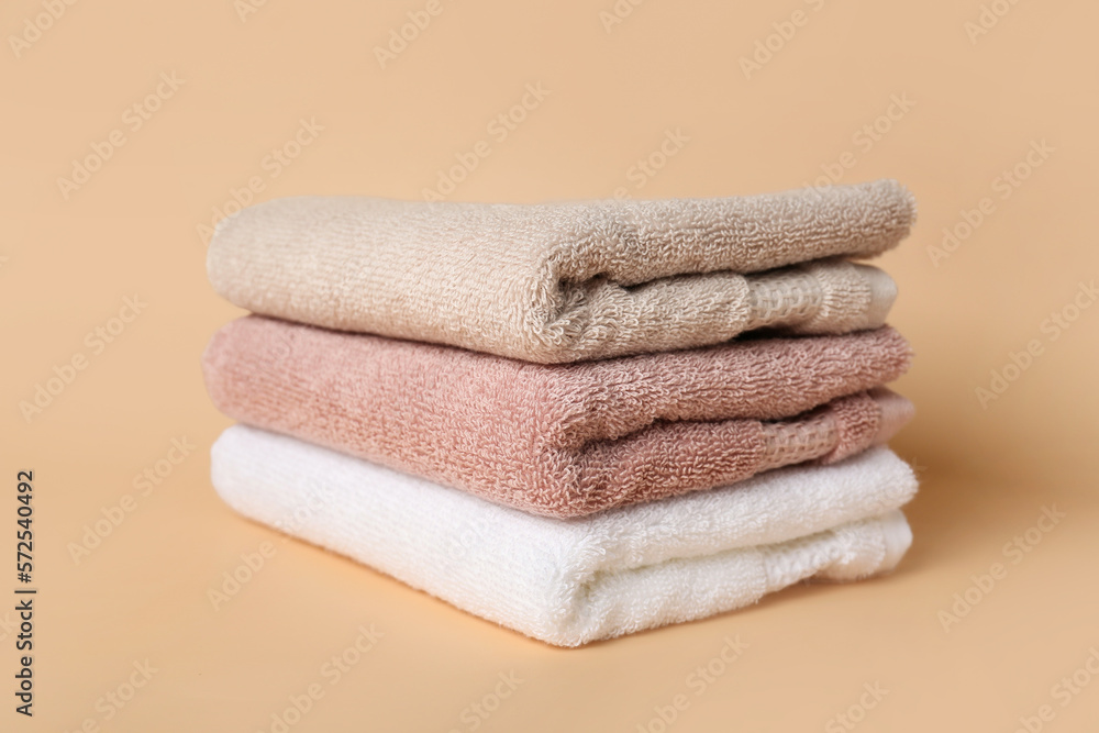 Stack of clean folded towels on color background