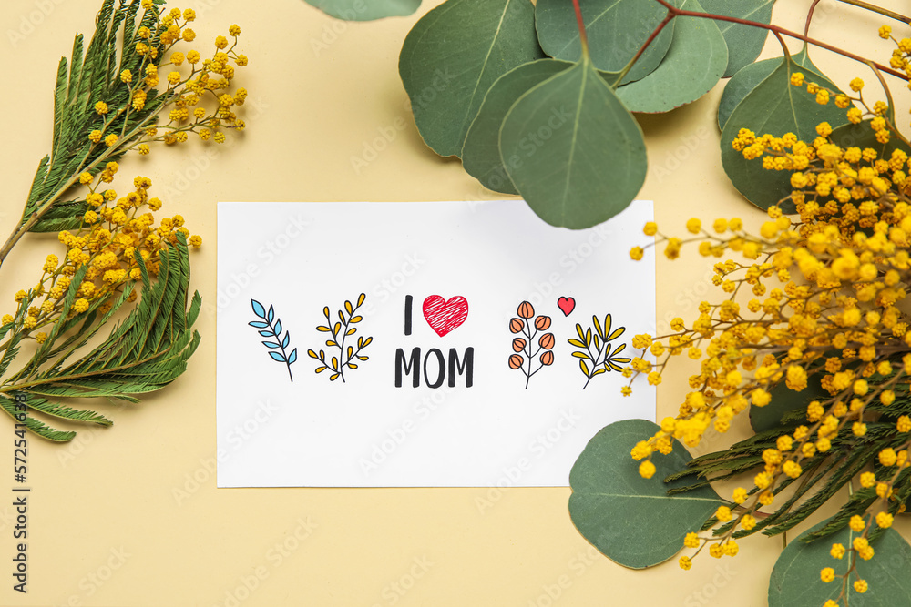 Composition with greeting card and mimosa flowers for Mothers day celebration on color background