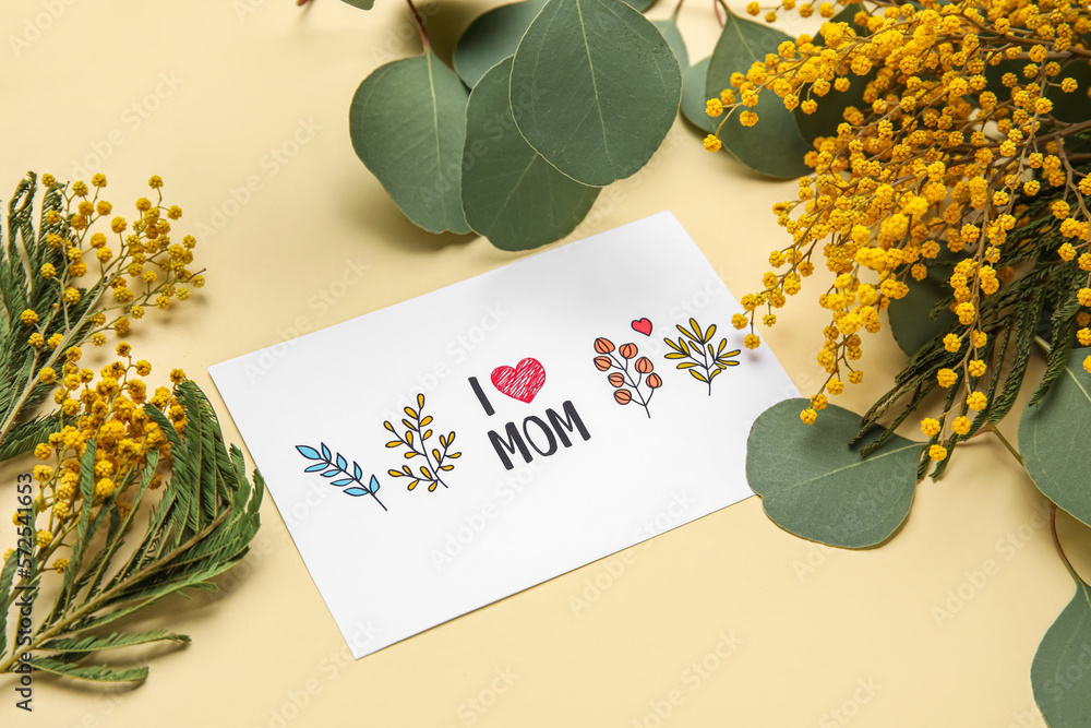 Composition with greeting card and mimosa flowers for Mothers day celebration on color background, 