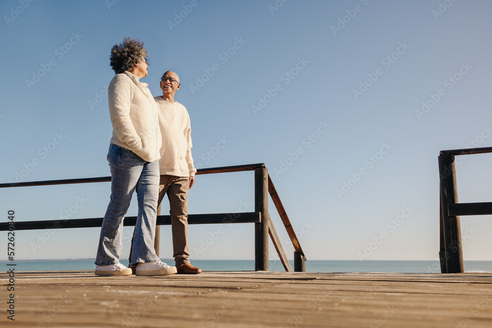 Senior couple taking a stroll along a foot bridge at the beach