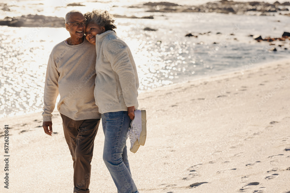 Happy senior couple embracing each other while walking on the beach