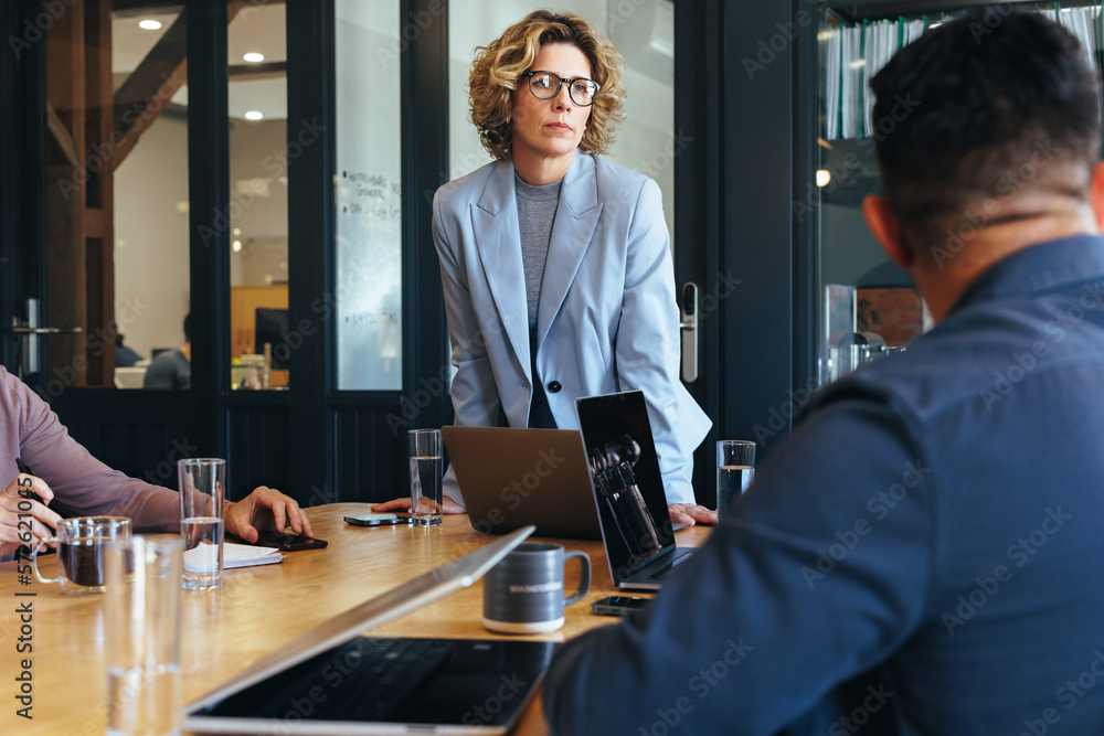 Mature business woman having a meeting with her team in an office