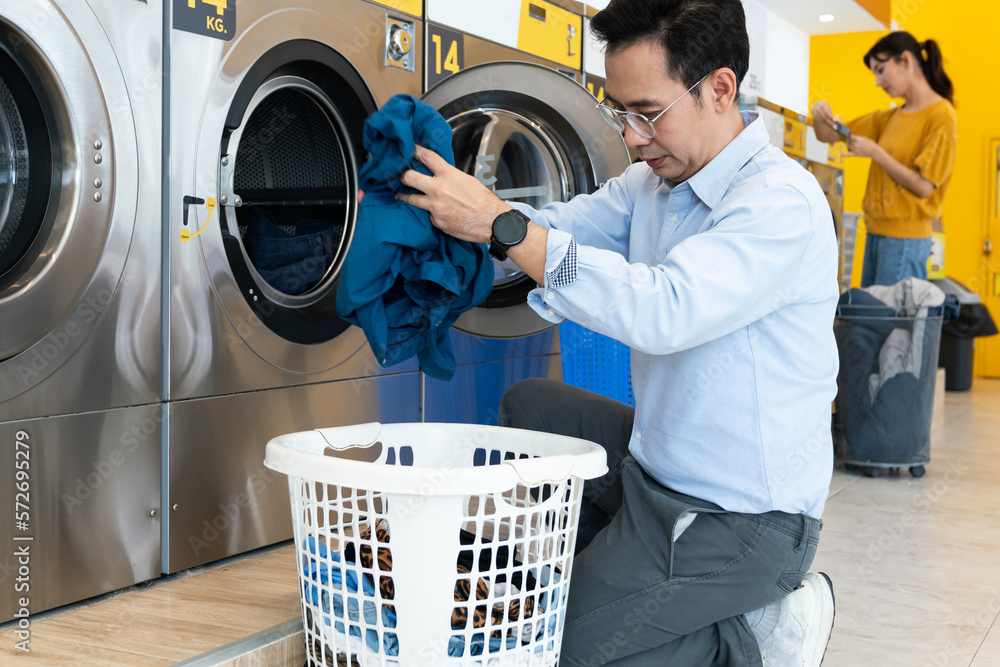 Asian people using qualified coin operated laundry machine in the public room to wash their cloths. 