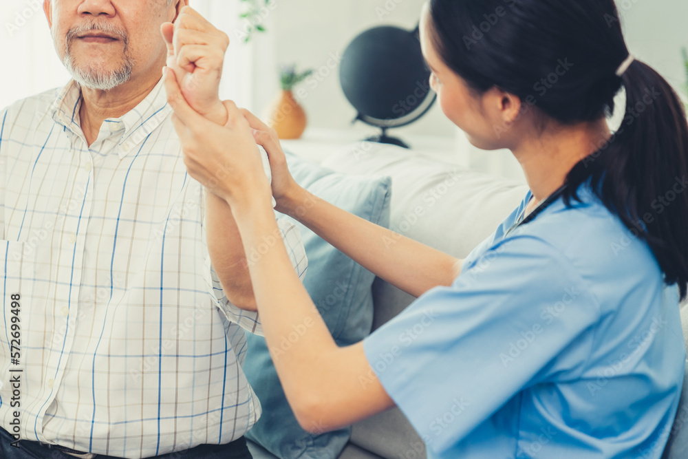 Caring young female doctor performing osteopathy treatment for a contented senior patient. At-home m