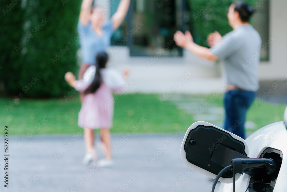 Focus closeup electric vehicle recharging battery from home electric charging station with blurred f