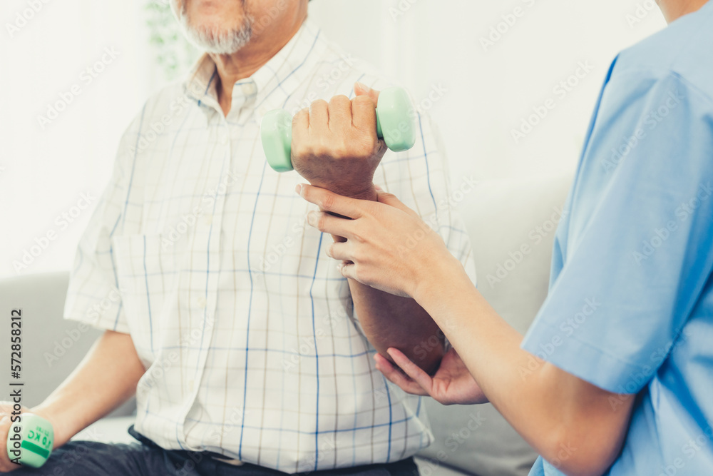 Contented senior patient doing physical therapy with the help of his caregiver. Senior physical ther