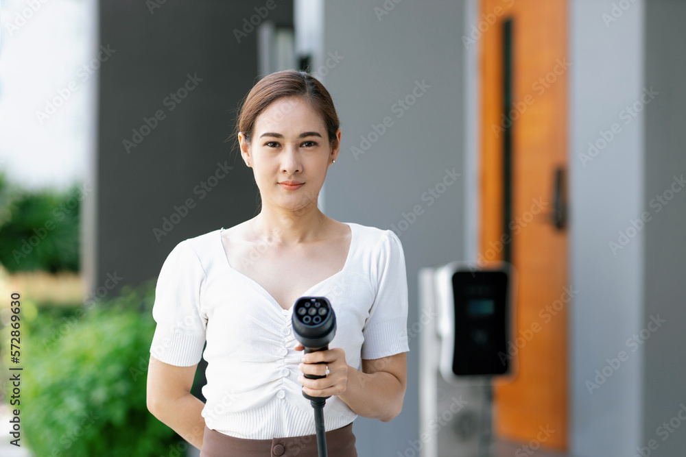 Closeup man holding and pointing an EV plug for electric vehicle at camera as progressive idea of al