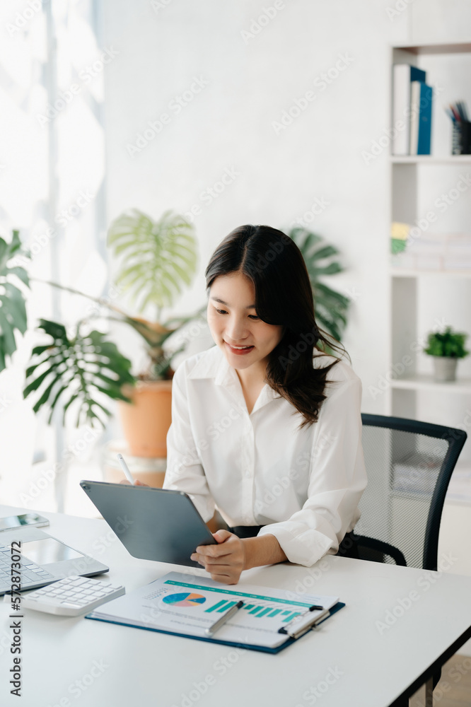 Young beautiful woman using laptop and tablet while sitting at her working place. Concentrated at wo