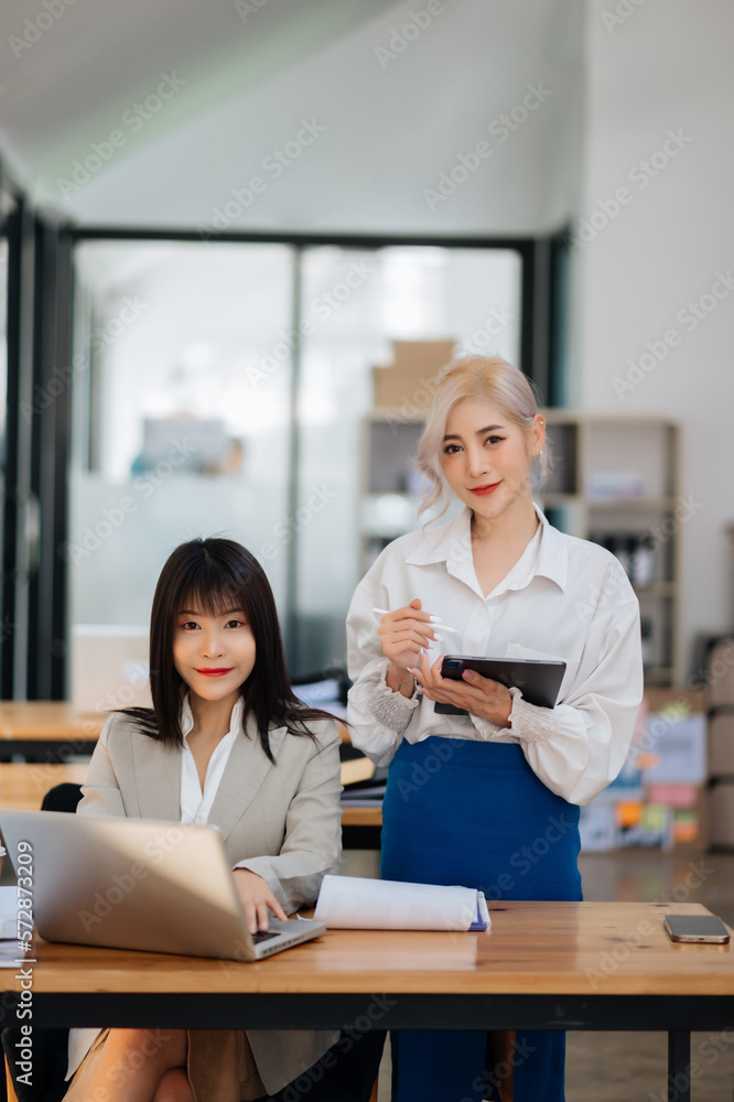 Businesswoman leading team meeting and using tablet and laptop computer with financial in office.