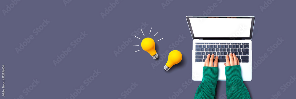 Person using a laptop computer and light bulbs - Flat lay