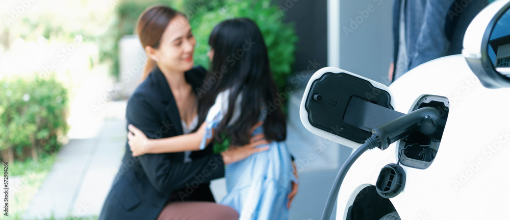 Focus closeup electric vehicle recharging battery from home electric charging station with blurred f