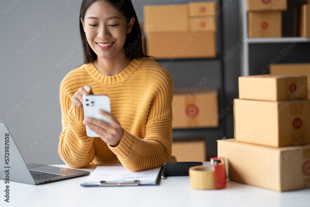 Young Adorable Asian online business owner using her smartphone to gather more information while sit