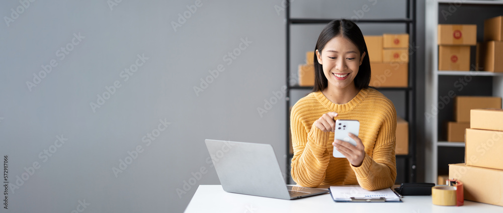 Young Adorable Asian online business owner using her smartphone to gather more information while sit