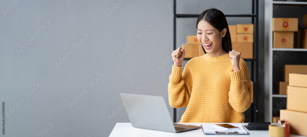 Happy young online business shop owner feeling excited about her sale record in recent month, celebr