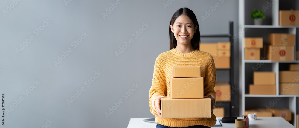 Adorable Asian woman holding the parcel boxes for her customers, online Sme business concept.