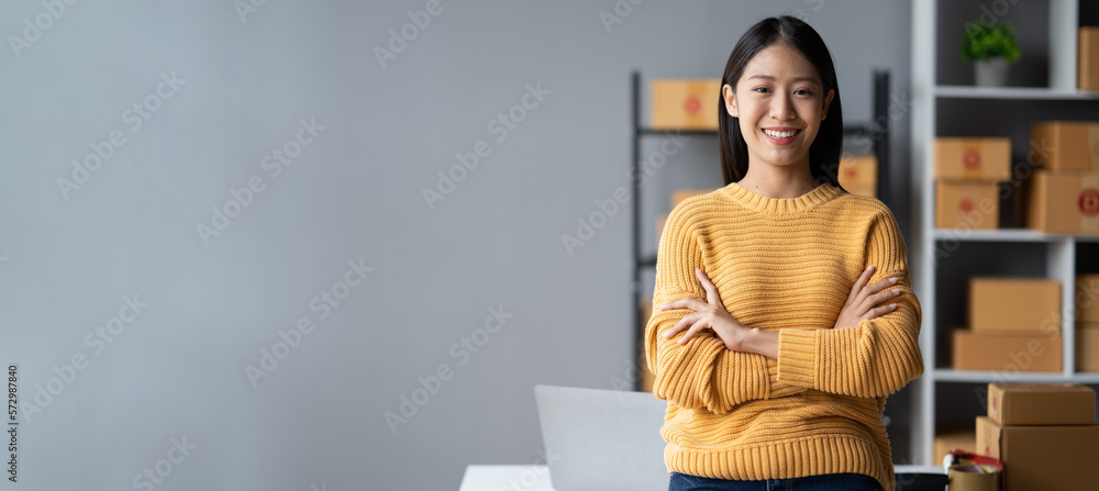 Portrait of young confident Asian small business owner standing in her room and smiling, feeling con