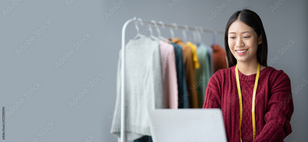 Asian beautiful cloth owner using laptop computer while planning her new concept for her new collect