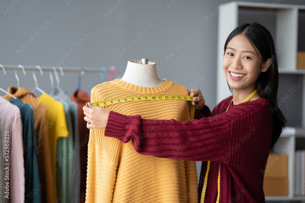 Young small cloth shop owner measuring the size for her customer with the clothes mannequin in her s