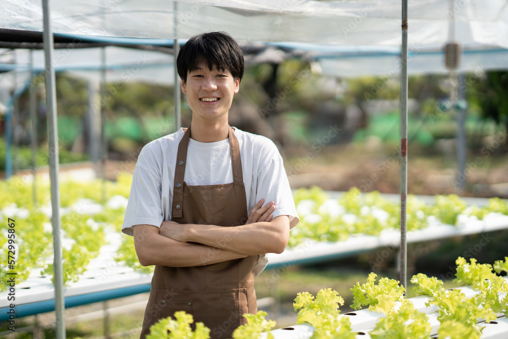 Portrait of young Asian male farm worker standing with confident in the hydroponics farm.