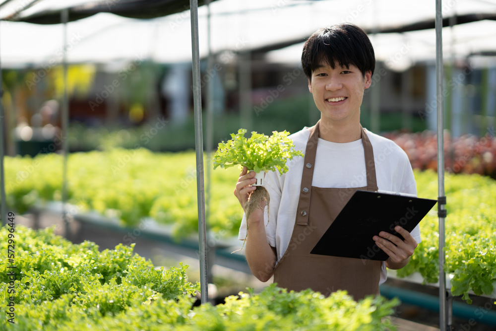 Young handsome Asian farm worker working in the farm while collect and write data on the document.