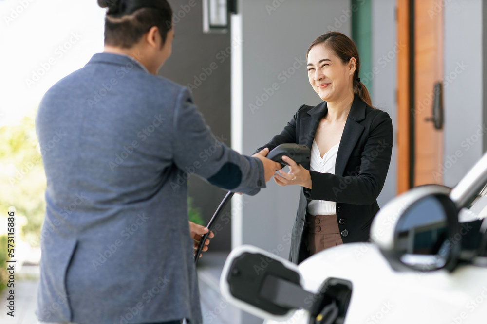 Concept of a progressive young couple with home charging station for an electric vehicle, encouragin