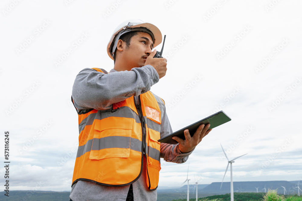 Engineer working on a wind farm atop a hill or mountain in the rural. Progressive ideal for the futu