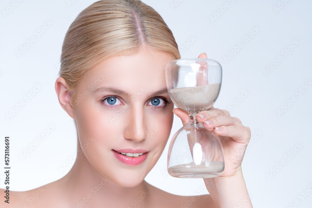 Closeup personable model holding hourglass in beauty concept of anti-aging skincare treatment. Young