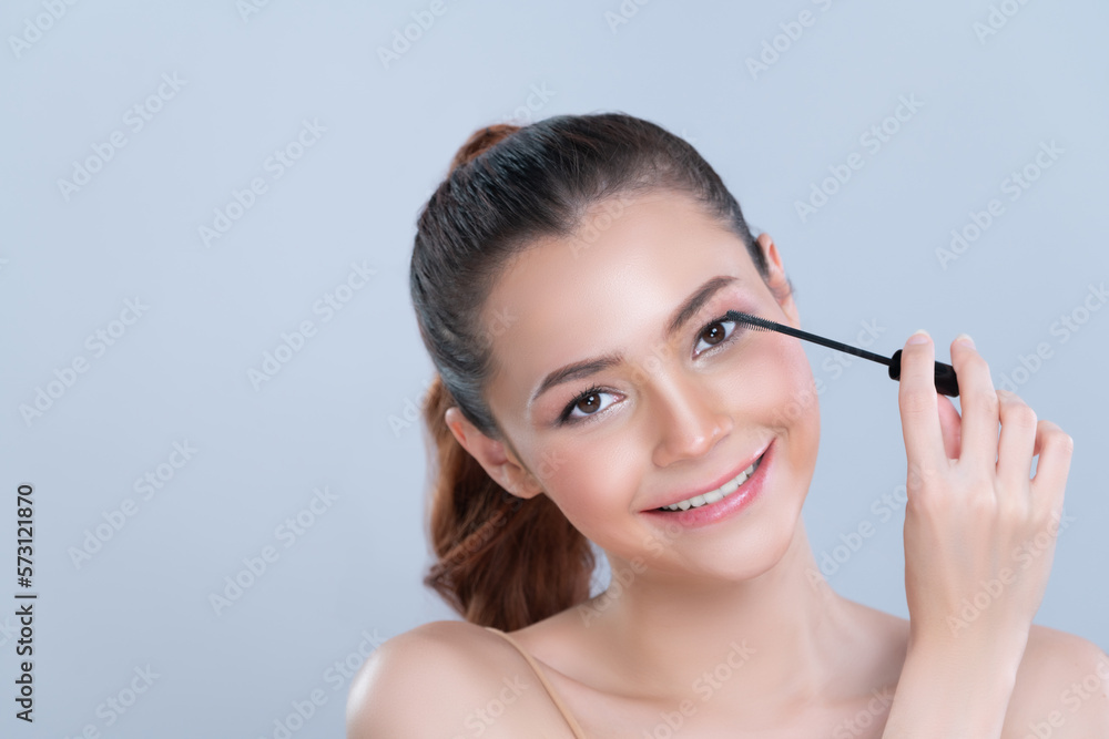 Closeup woman with blond hair putting glamorous black mascara with brush in hand on long thick eyela