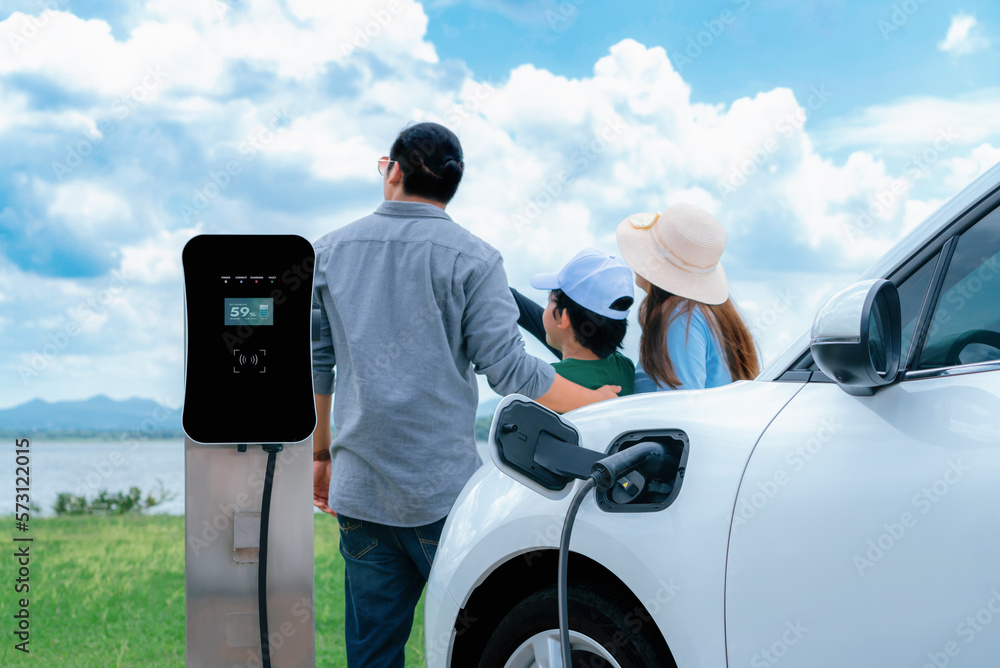 Concept of progressive happy family with electric vehicle enjoy their time at natural outdoor scenic