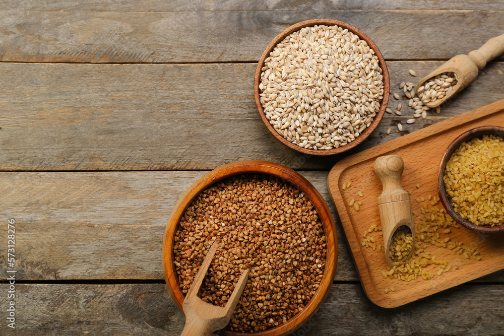 Bowls with different cereals on wooden background