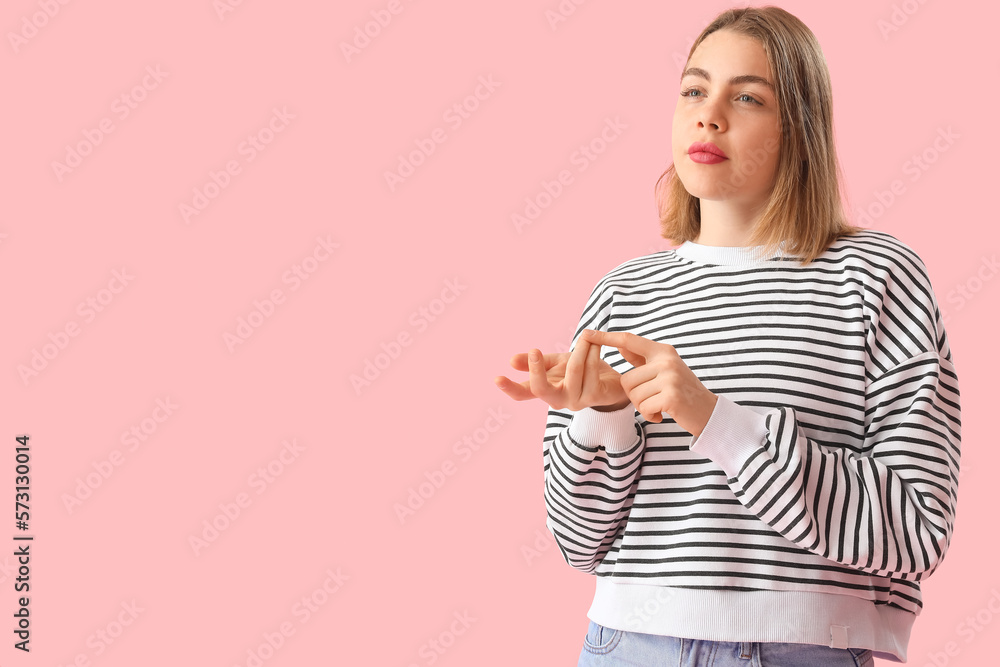 Young woman in striped sweatshirt counting on pink background