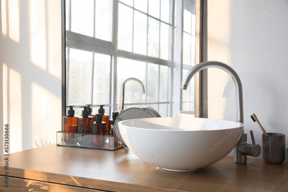 Sink with bath accessories on table in room