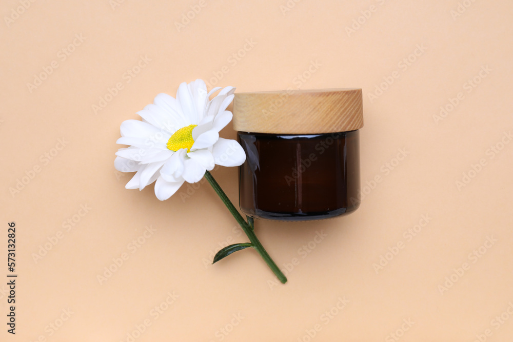 Jar of cosmetic product and chamomile flower on color background