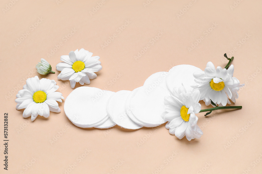 Composition with cotton pads and chamomile flowers on color background