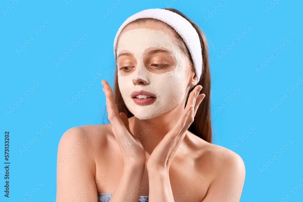 Young woman with applied turmeric mask on blue background, closeup