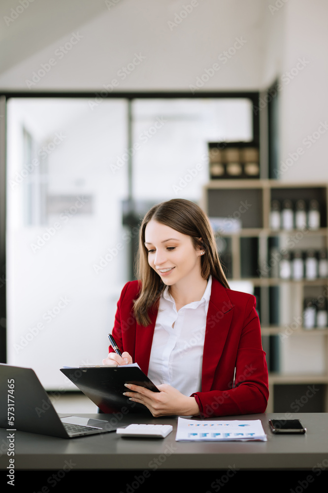 Young attractive Asian woman smiling thinking planning writing in notebook, tablet and laptop workin