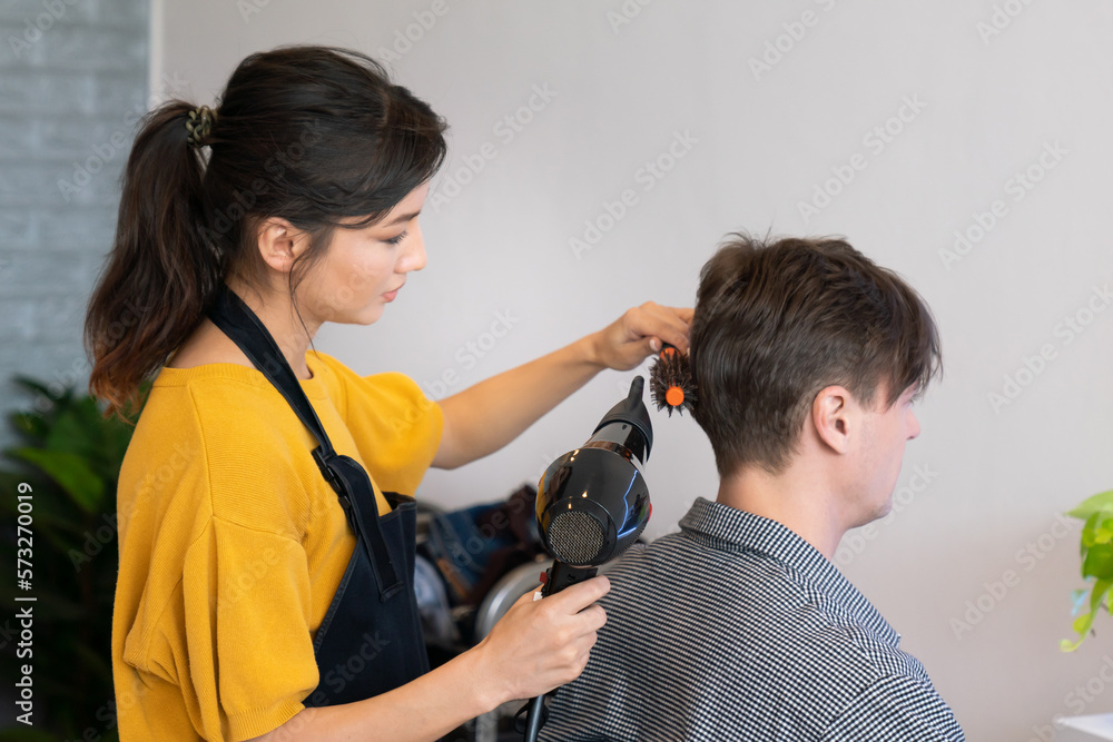 Asian female barber making haircut for male customer with male hairstyle in qualified barbershop. Me