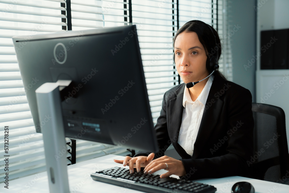 Competent female operator working on computer and talking with clients. Concept relevant to both cal