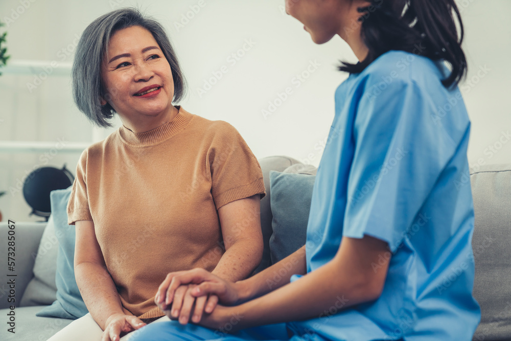 A contented senior woman visited by her personal caregiver and hold each others hands.