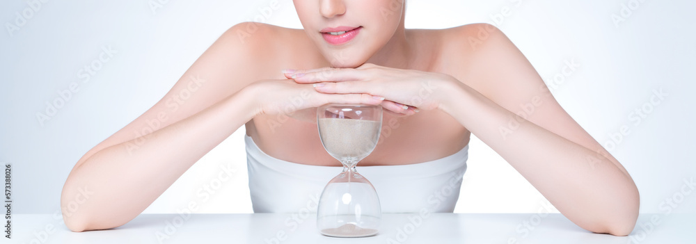 Closeup personable model holding hourglass in beauty concept of anti-aging skincare treatment. Young