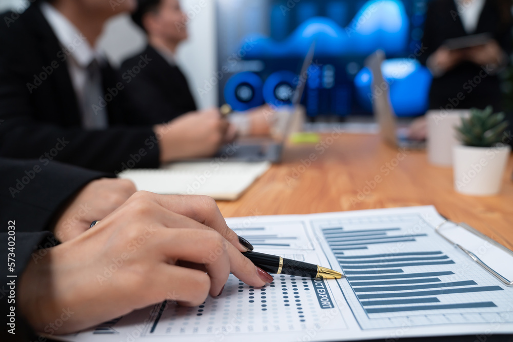 Focus closeup on BI dashboard on meeting desk with blur businesspeople in background analyzing data 