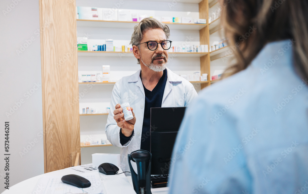 Mature pharmacist assisting a patient over the counter