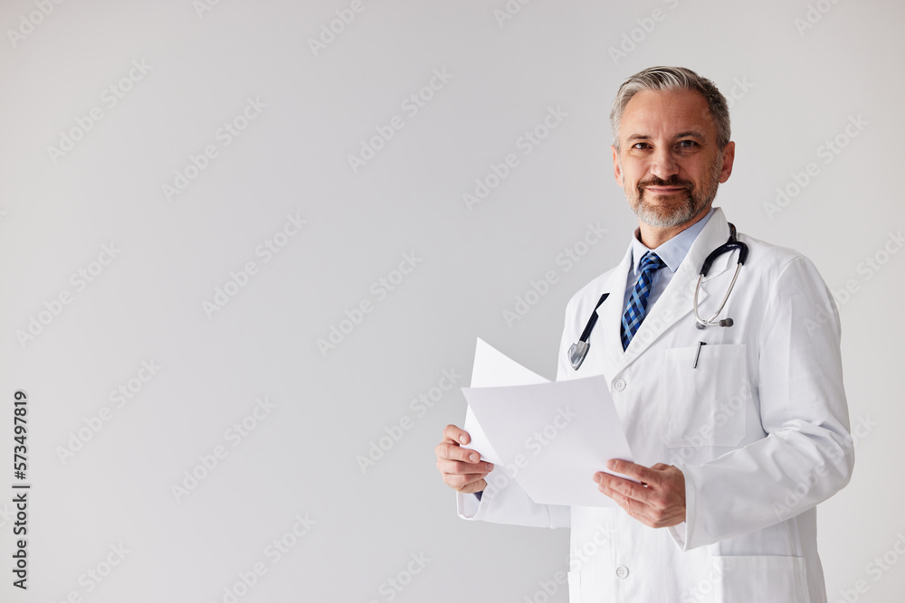 Portrait of a senior male doctor, holding papers with patients results.