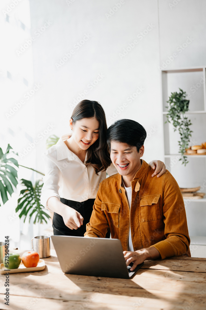 Two Asian business workers talking on the smartphone and using laptop at the home office.