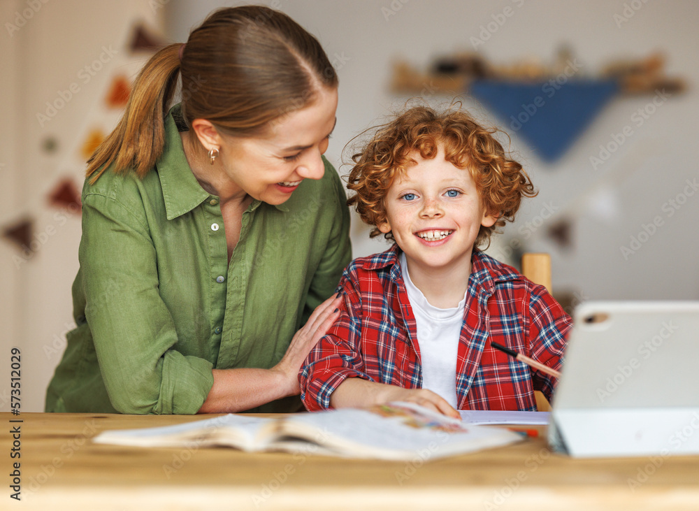 Cheerful mother doing homework with son at home