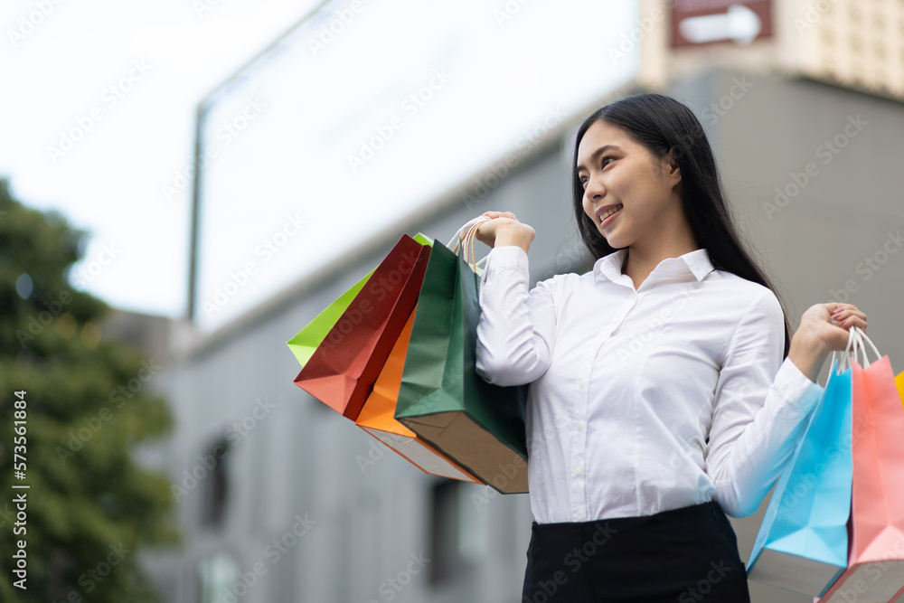 Cheerful and attractive young Asian woman carrying shopping bags. Female tourist carrying shopping b