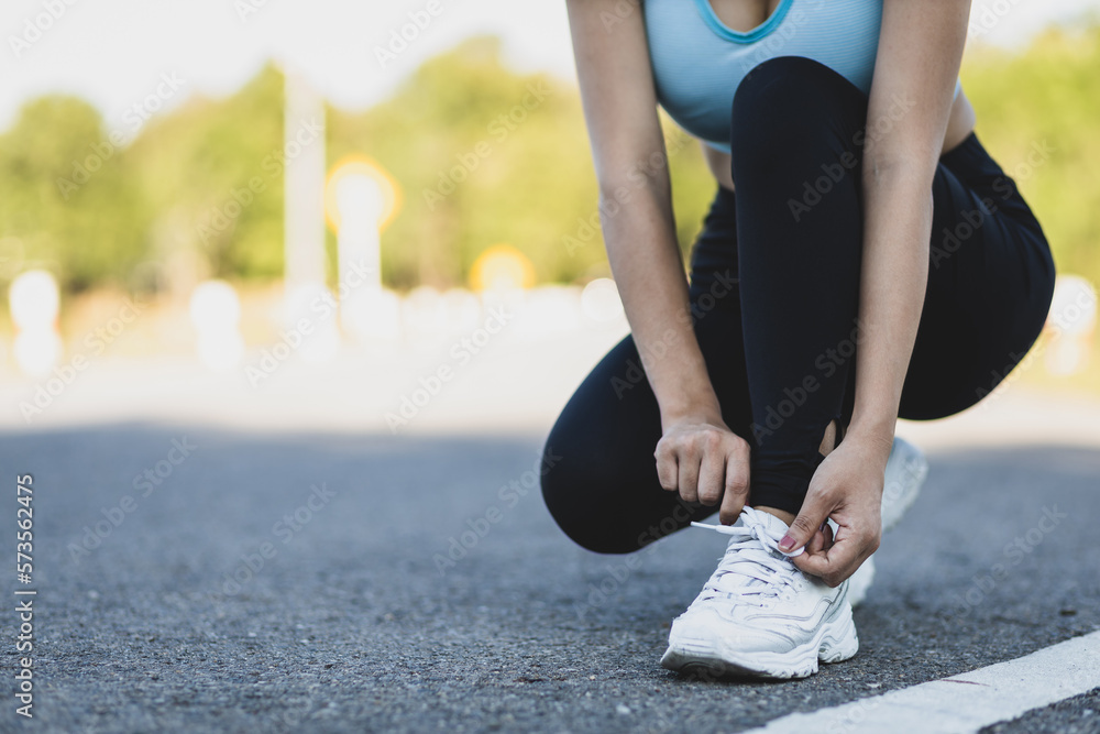 Woman running athlete tying shoelaces. Get ready to start exercising or running. Healthy lifestyle c