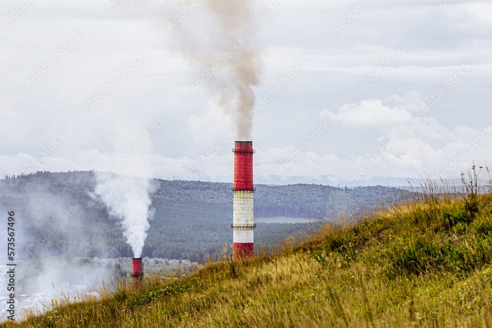 concept of environmental pollution. pipes with smoke on background of forest and mountain